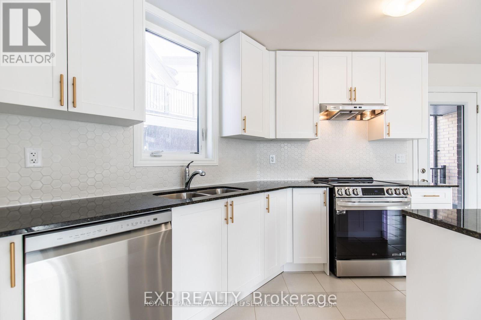 A modern kitchen with white cabinets and a black countertop.