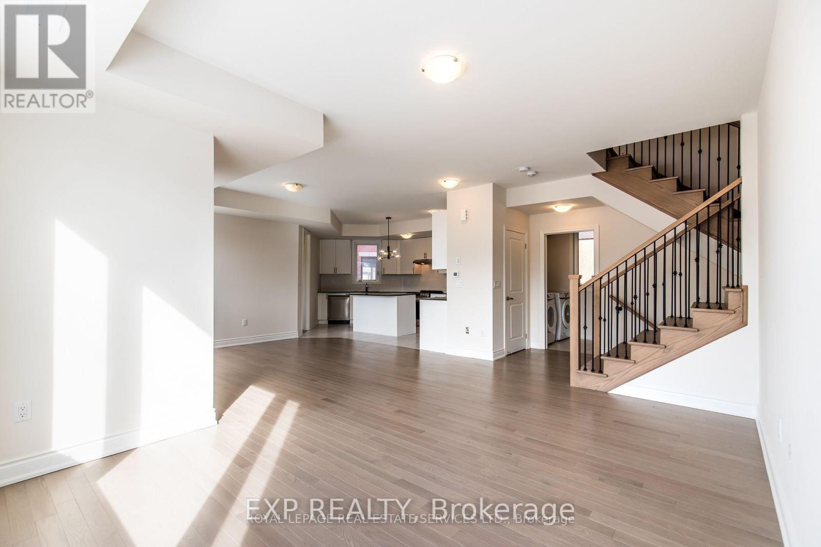 A spacious living room with a staircase leading to the upper floor.