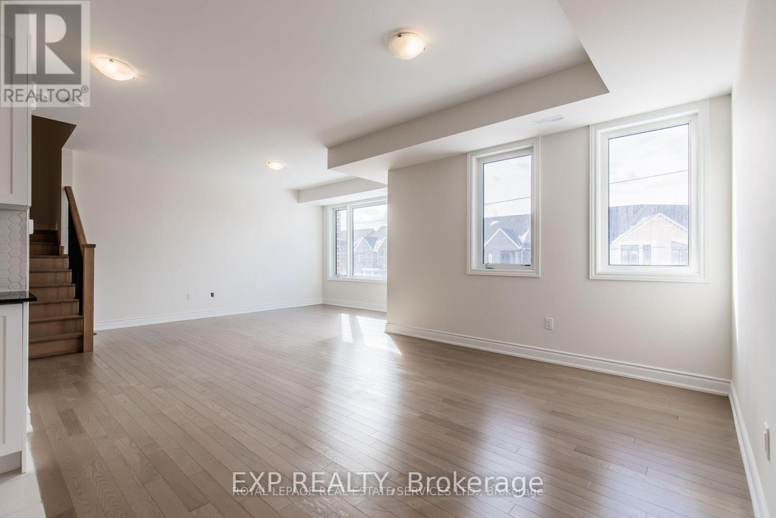 A spacious room with wooden flooring and white walls.