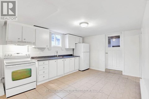 A white kitchen with a stove, cabinets, and a window.