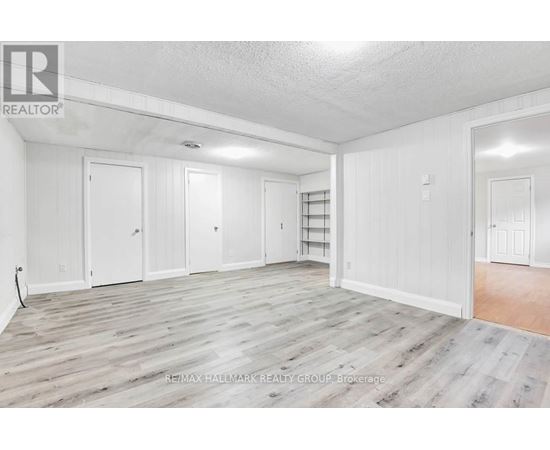 A spacious room with white walls and wooden flooring.