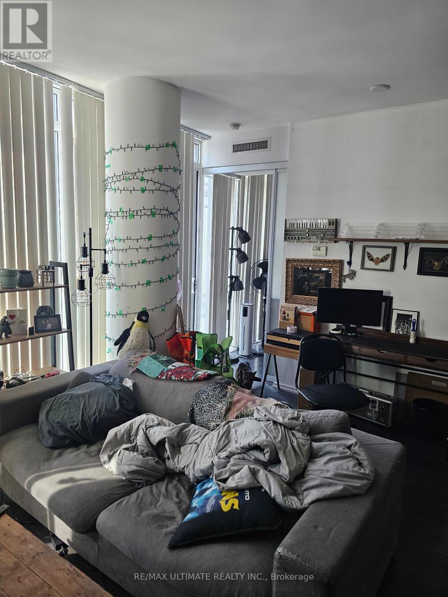 A living room with a grey couch and a TV in the background.