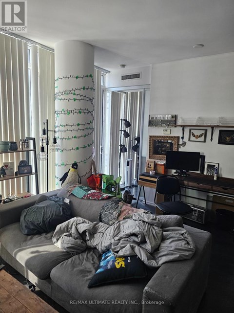 A living room with a grey couch and a TV in the background.
