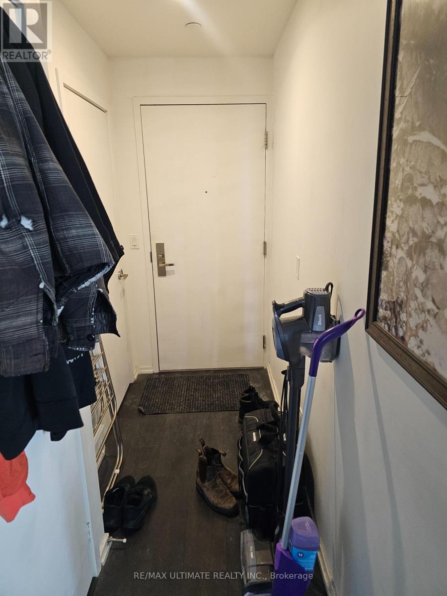 A hallway with a broom and a pair of shoes on the floor.