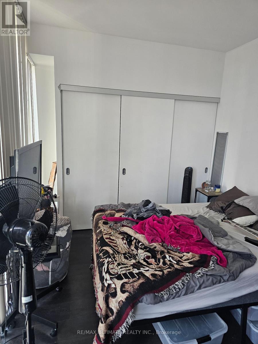 A bedroom with a bed, a fan, and a closet.