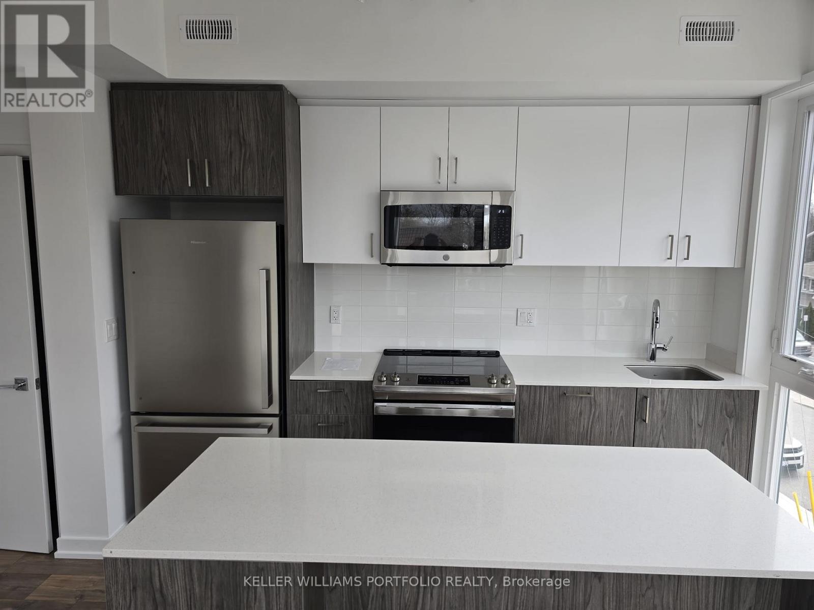 A kitchen with a white counter top and stainless steel appliances.