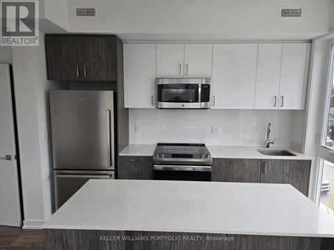 A kitchen with a white counter top and stainless steel appliances.