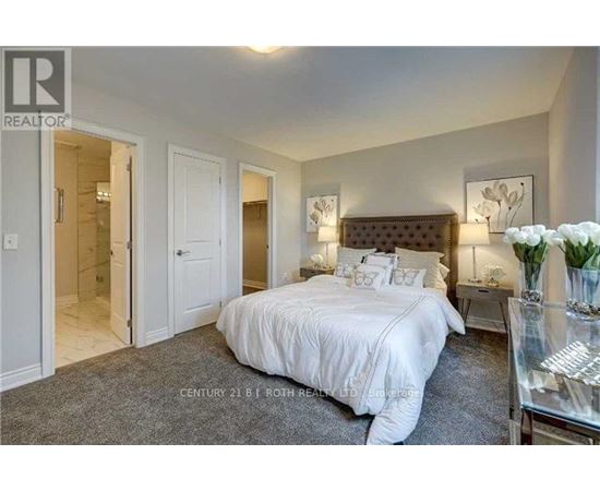 A bedroom with a bed, nightstands, and a vase of flowers.
