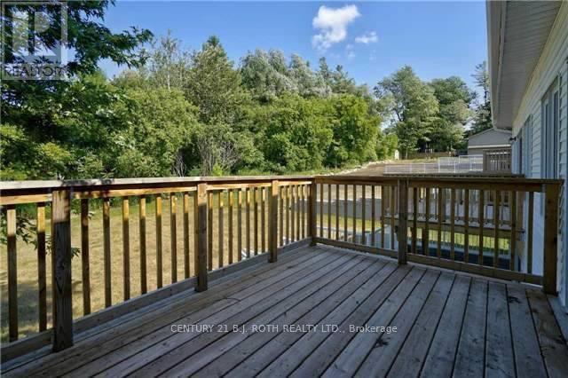 A wooden deck with a railing and a view of trees and a house.