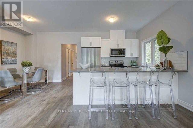 A modern kitchen with white cabinets and a bar area.