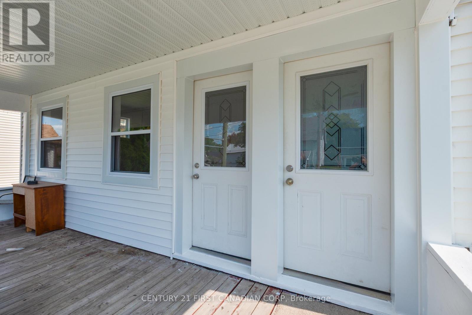 A white house with a porch and two doors.