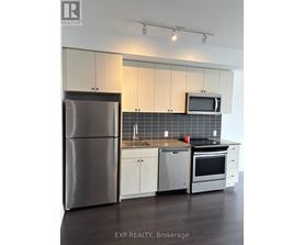 A kitchen with white cabinets and a stainless steel refrigerator.