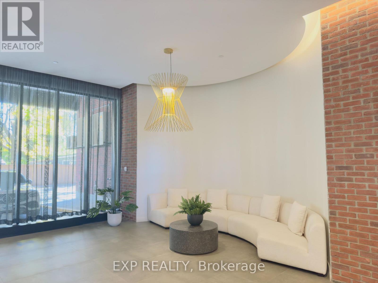 A living room with a white couch and a hanging light fixture.