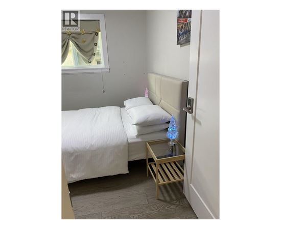 A bedroom with a bed, nightstand and a window.
