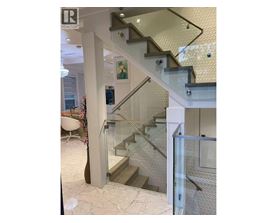 A staircase with a glass railing and a white wall.