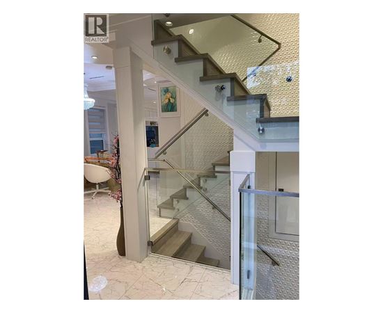 A staircase with a glass railing and a white wall.