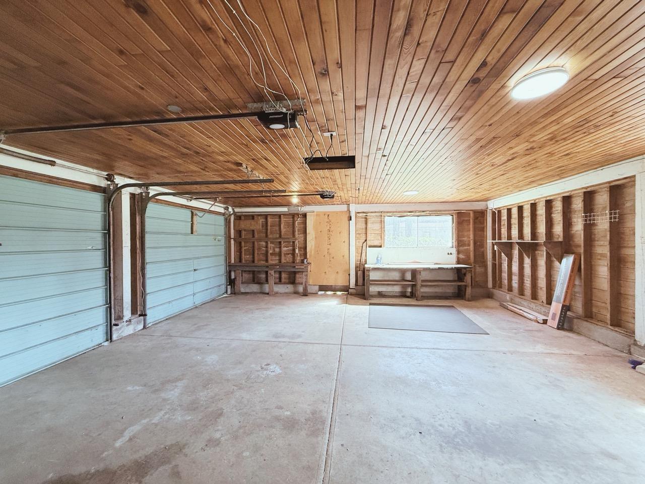 A spacious garage with wooden walls and ceiling, and a concrete floor.