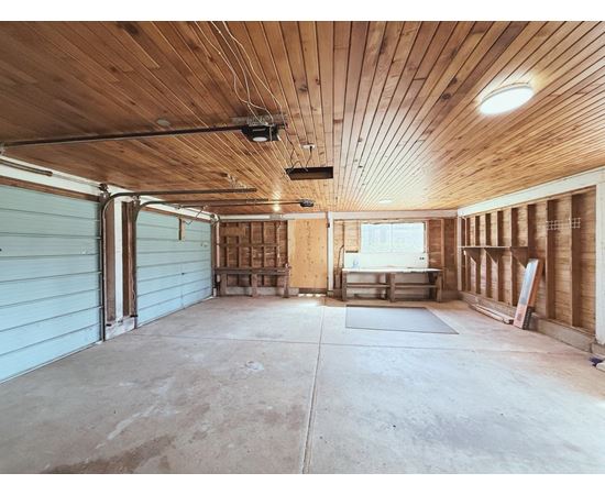 A spacious garage with wooden walls and ceiling, and a concrete floor.