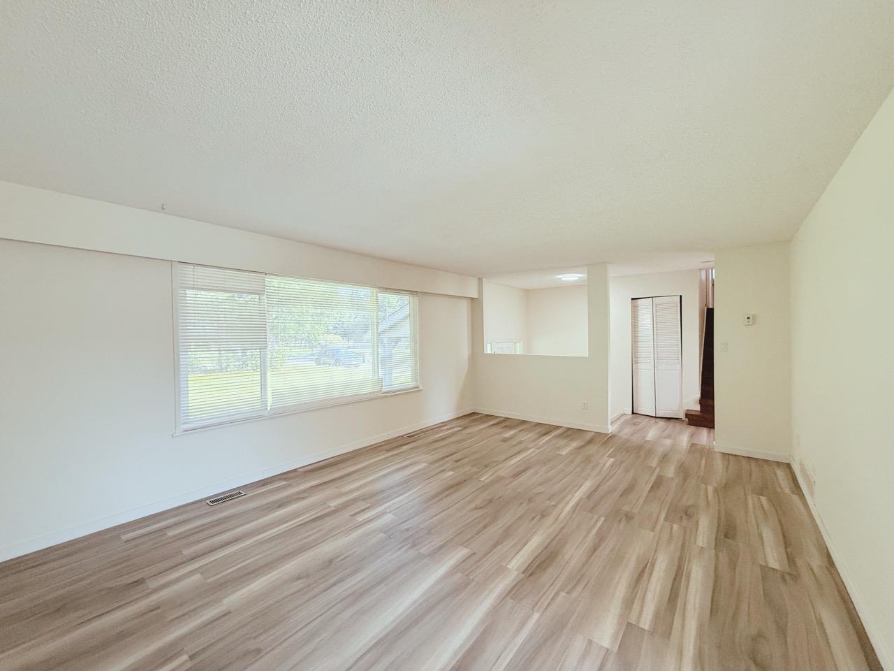 A room with wooden flooring and a window with blinds.