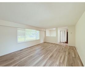 A room with wooden flooring and a window with blinds.