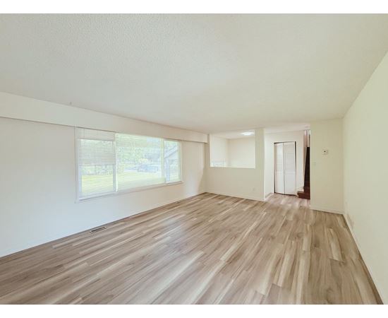 A room with wooden flooring and a window with blinds.