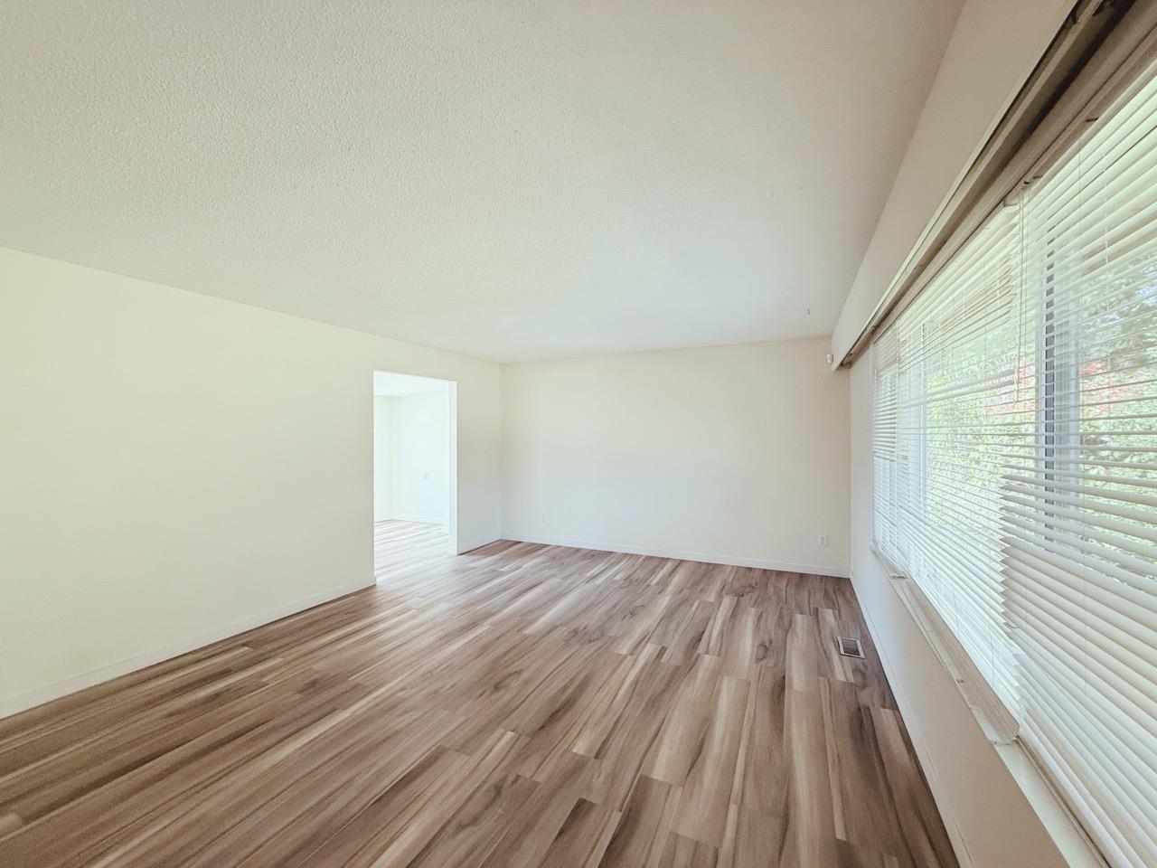 A room with wooden flooring and a window with blinds.