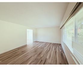 A room with wooden flooring and a window with blinds.