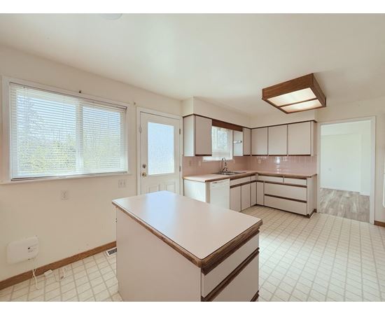 A kitchen with white cabinets and a white tile floor.