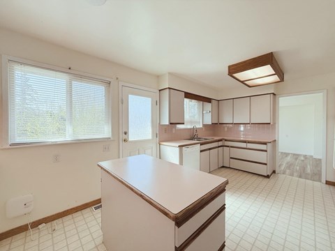 A kitchen with white cabinets and a white tile floor.