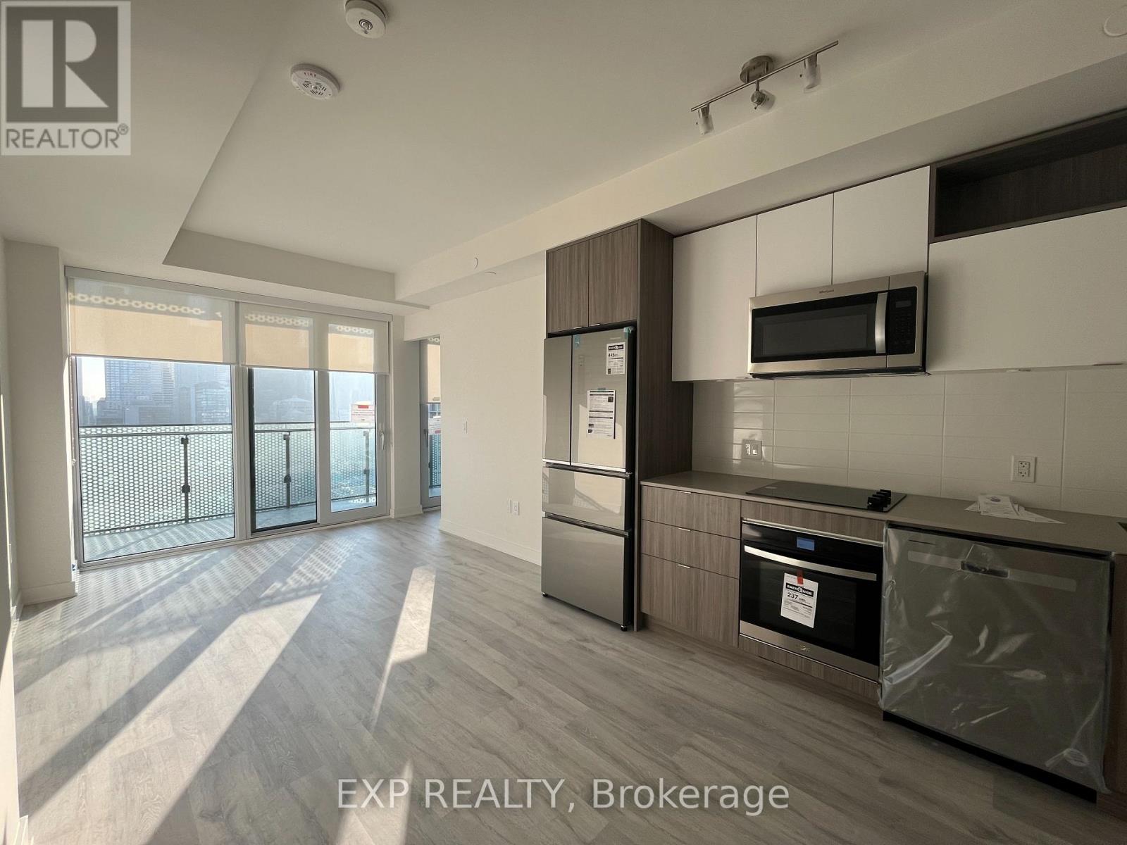 A kitchen with a refrigerator, oven, and microwave.