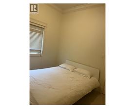 A bedroom with a bed, pillows, and a window with blinds.