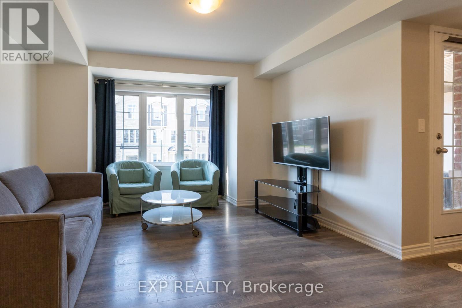 A living room with a couch, chairs, and a television.