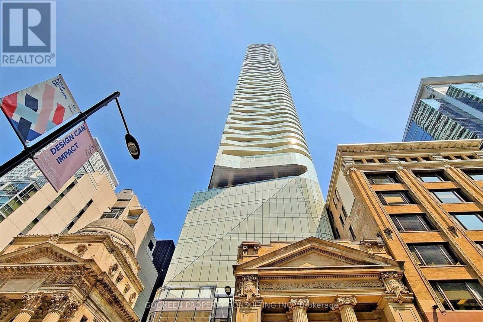 A tall building with a glass facade stands in front of a row of older buildings.
