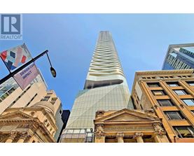 A tall building with a glass facade stands in front of a row of older buildings.