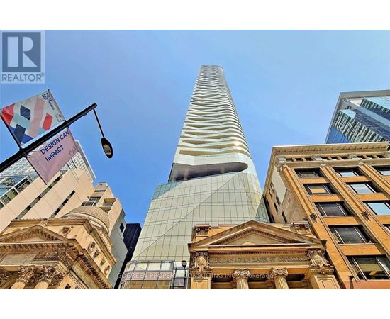 A tall building with a glass facade stands in front of a row of older buildings.