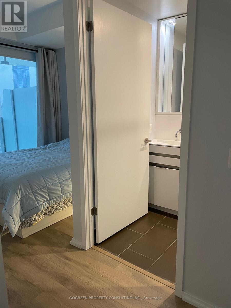 A bedroom with a bed, a sink, and a mirror.