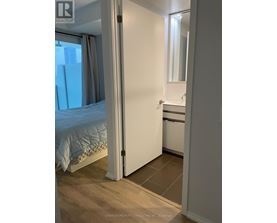 A bedroom with a bed, a sink, and a mirror.