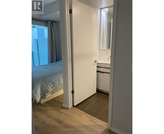 A bedroom with a bed, a sink, and a mirror.
