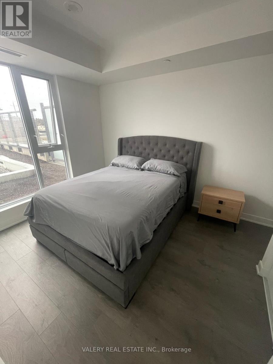 A bedroom with a large bed and a wooden nightstand.