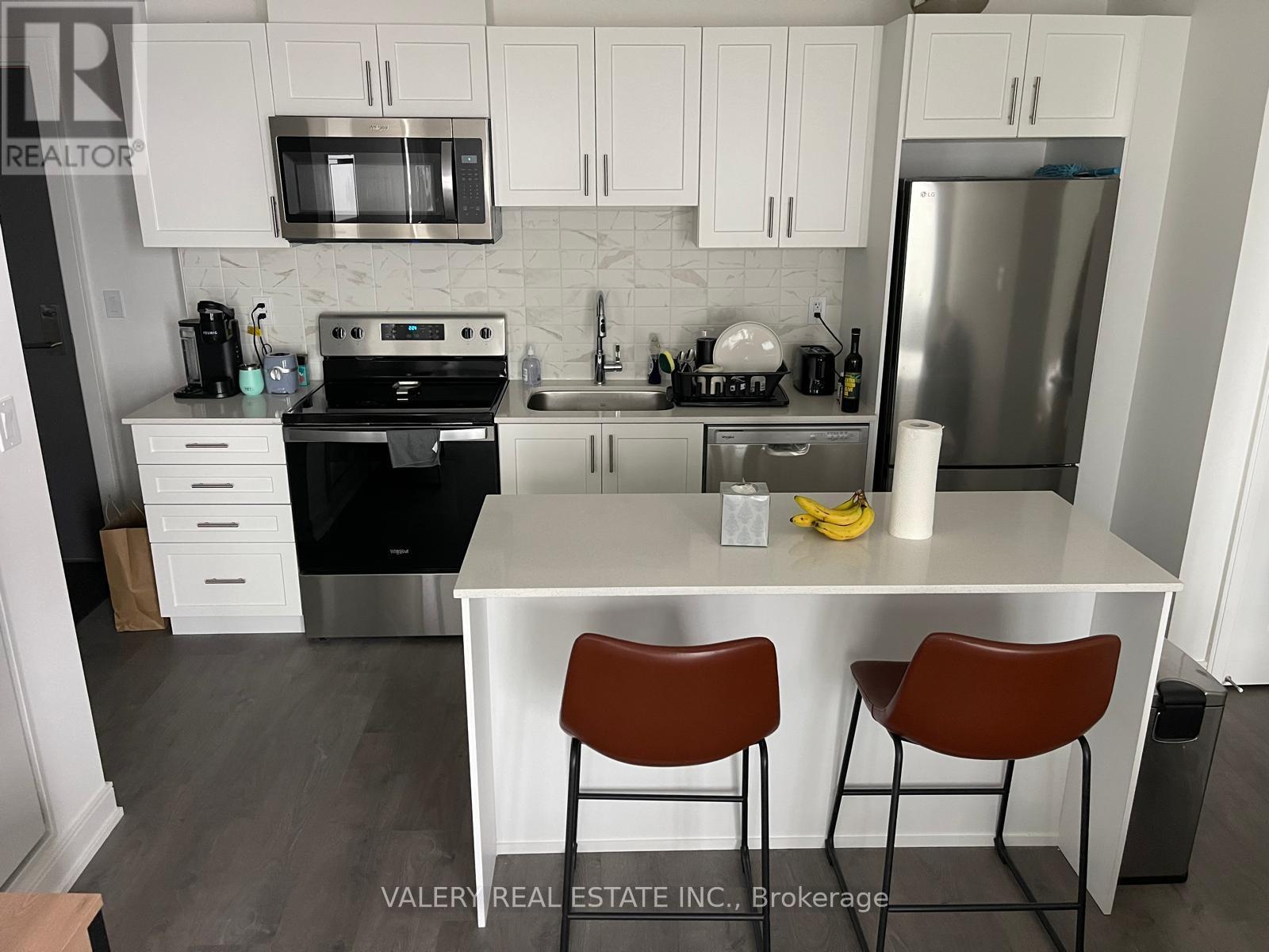 A kitchen with white cabinets and a stainless steel refrigerator.