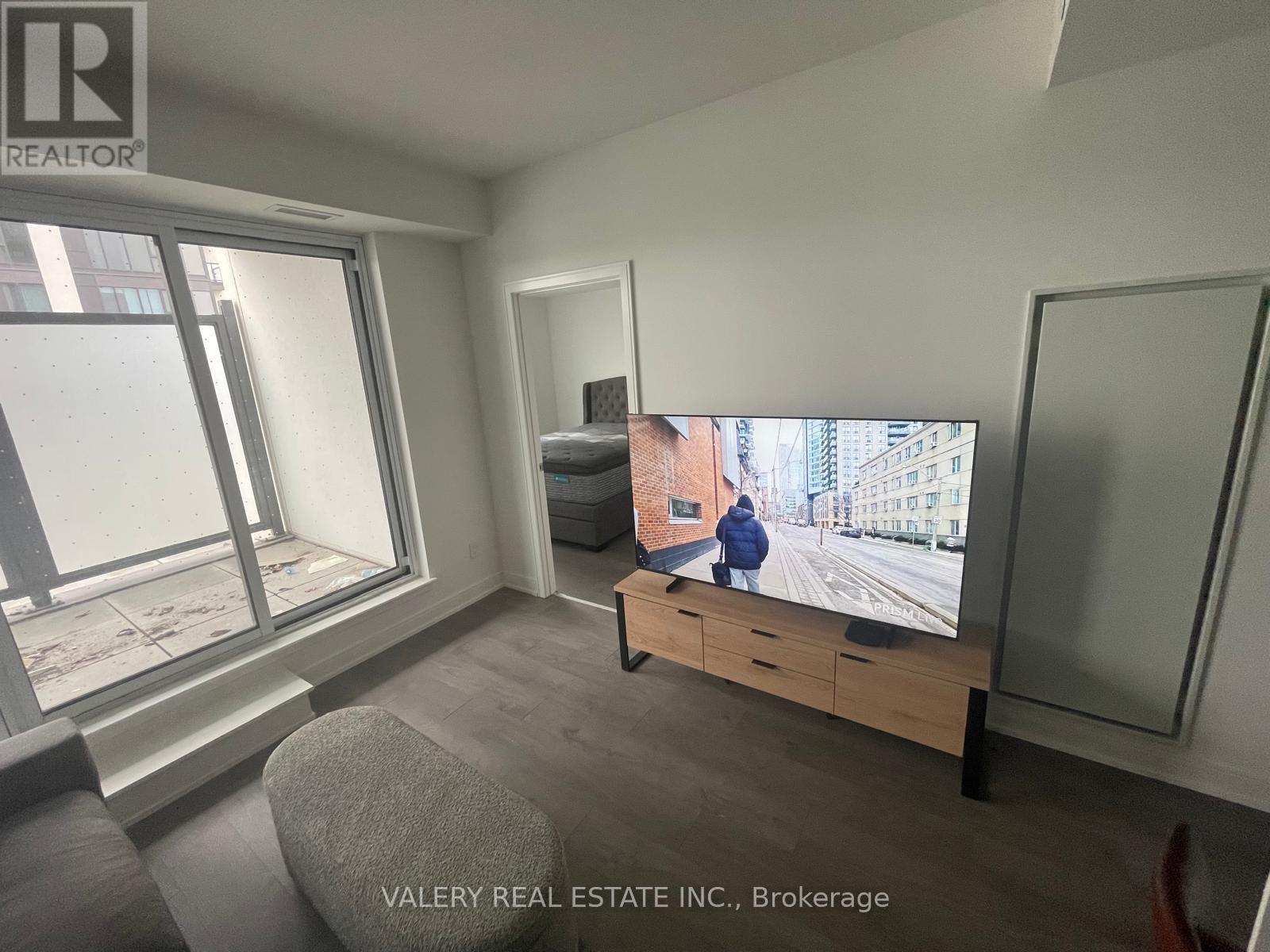 A living room with a flat screen TV and a large window.