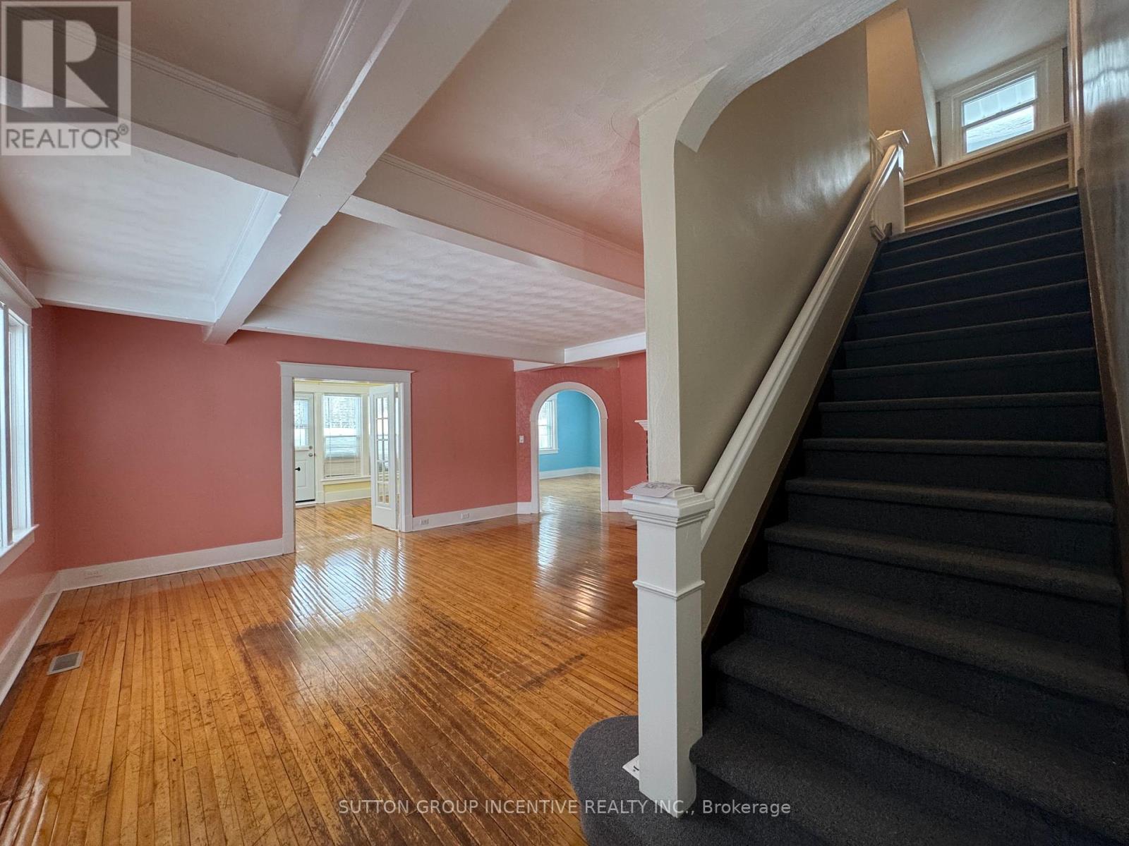 A room with wooden floors and a staircase leading to another room.
