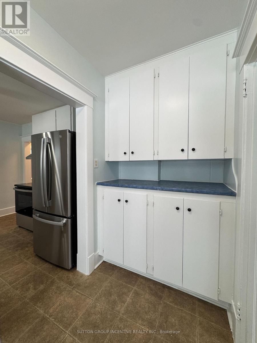 A kitchen with white cabinets and a refrigerator.