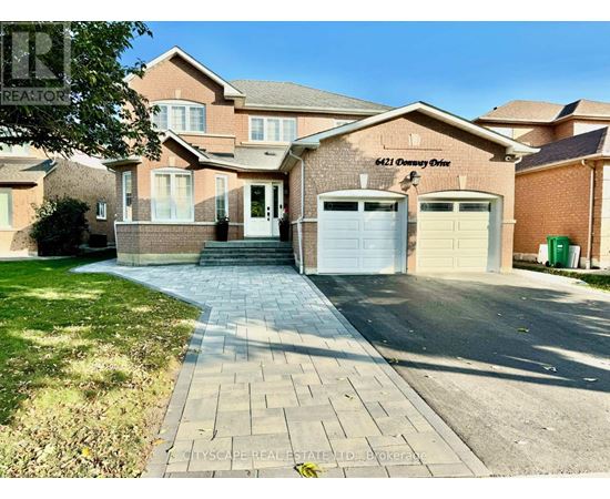 A brick house with a driveway in front of it.