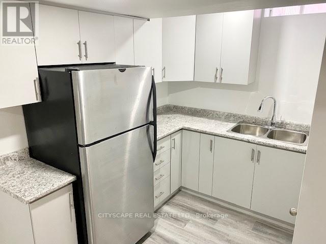A kitchen with a black refrigerator and white cabinets.