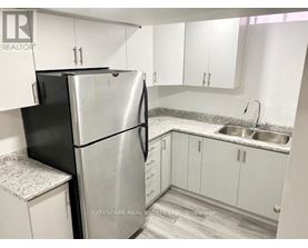 A kitchen with a black refrigerator and white cabinets.