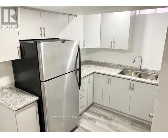 A kitchen with a black refrigerator and white cabinets.