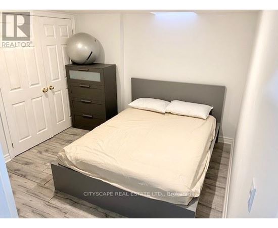 A bedroom with a bed, nightstand, and a door.