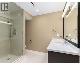 A bathroom with a glass shower stall and a sink with a mirror above it.
