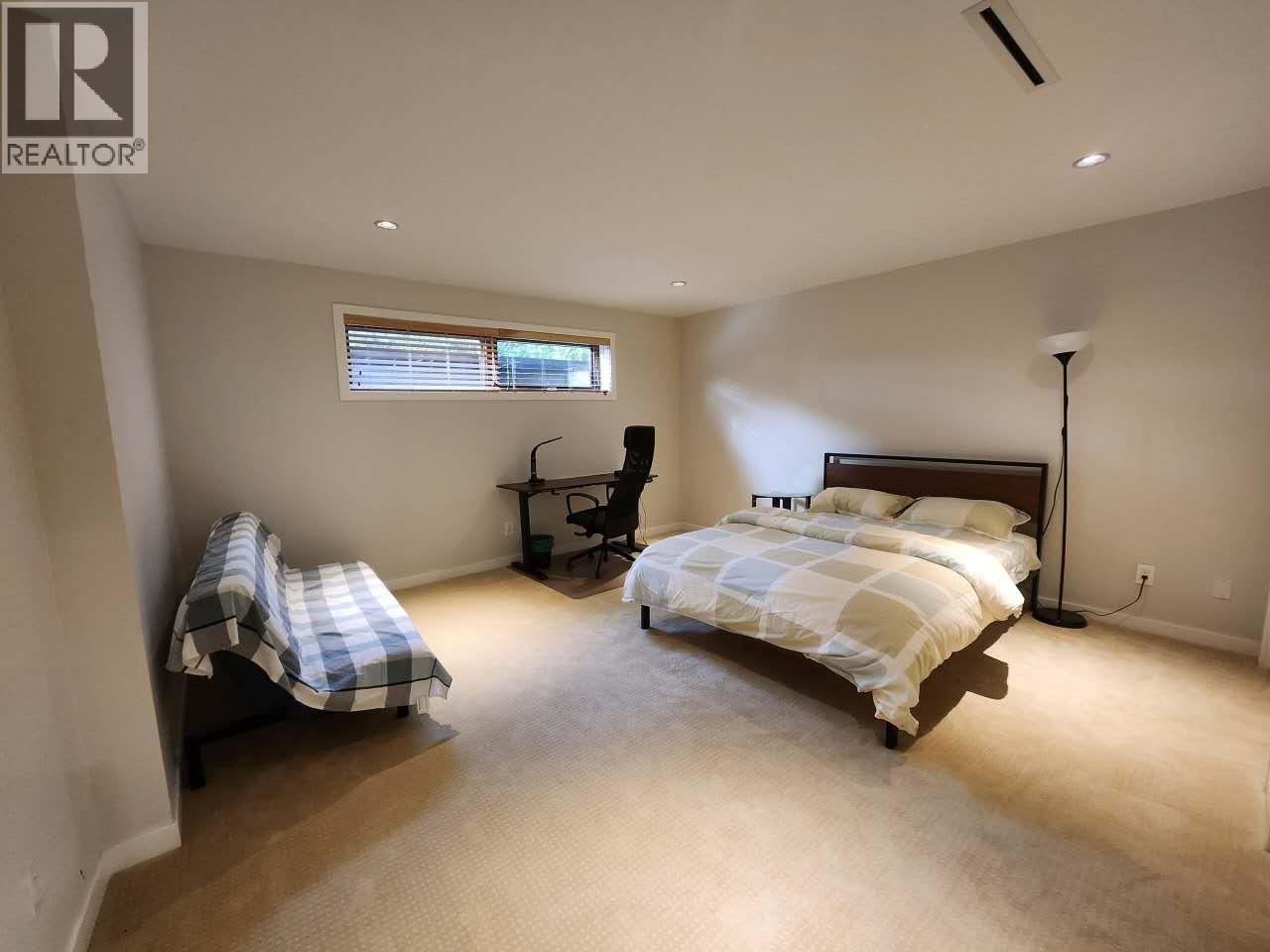 A bedroom with a bed, chair, and window.